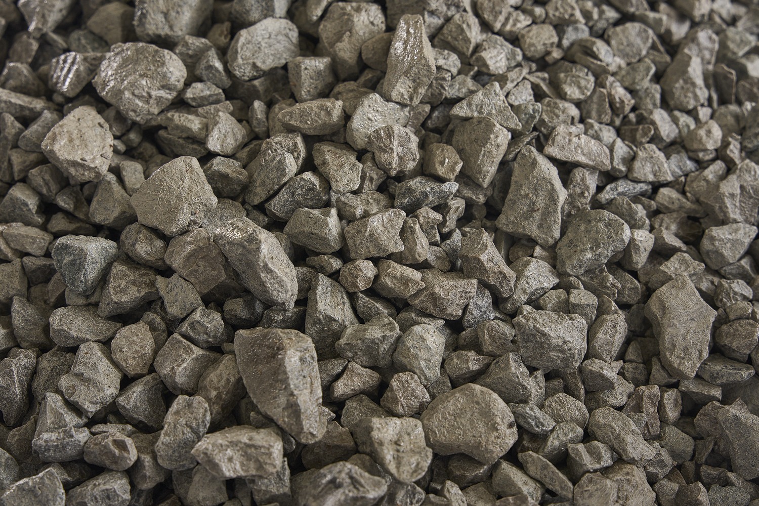 A close-up of a pile of small, rough gray rocks, showing various shapes and textures, suitable for construction or landscaping use.