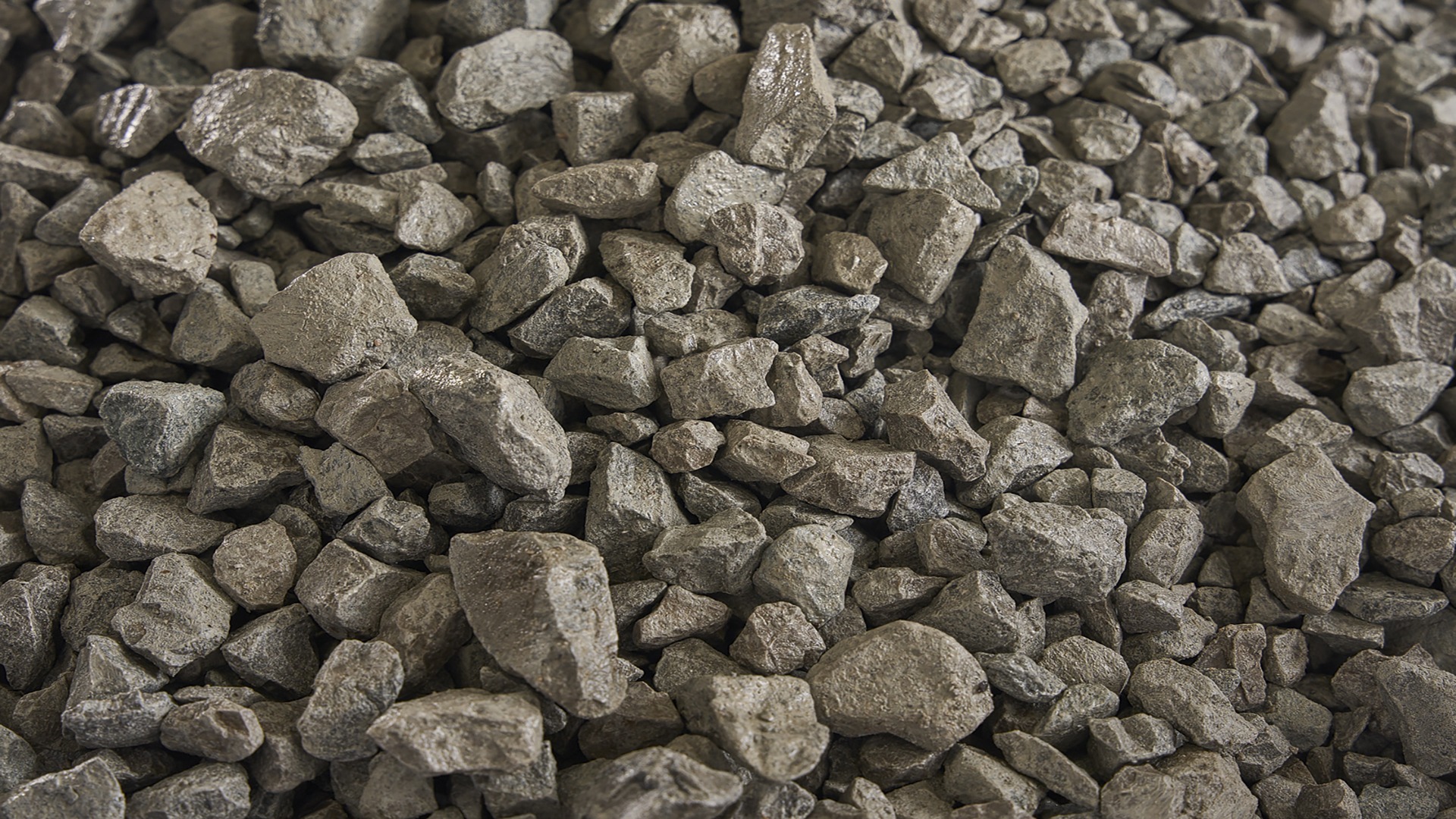 A close-up view of a pile of gray rocks or gravel, with varying shapes and sizes, creating a textured and rugged surface.